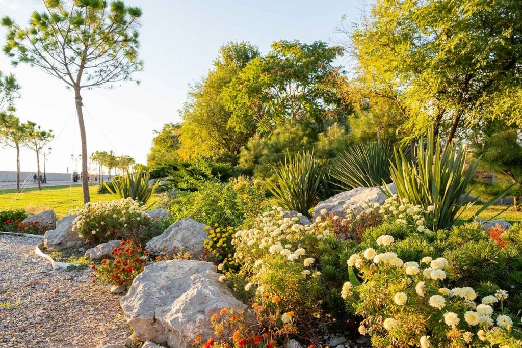 Rock garden border planted with white and yellow flowers beside a garden path