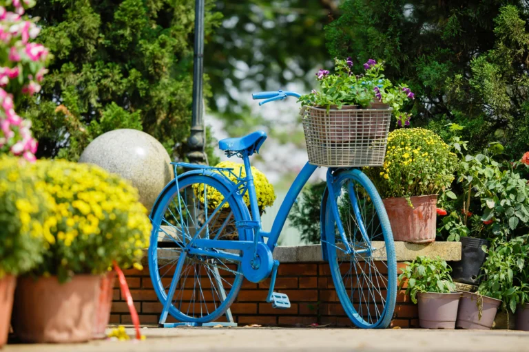 Blue bicycle with a flower basket among yellow blooms in a garden